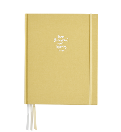 A closed 2024 Grande Planner Weekly Vertical - Limoncello with the handwritten inscription "two thousand twenty four" on the cover, featuring a ribbon bookmark and custom specifications by Emma Kate Co.