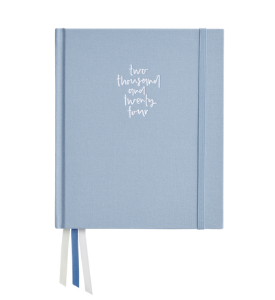 A luxe linen fabric cover blue journal with "2024 Signature Planner Daily - Amalfi" handwritten on the cover, suggesting it's a planner or diary for the year 2024 by Emma Kate Co.