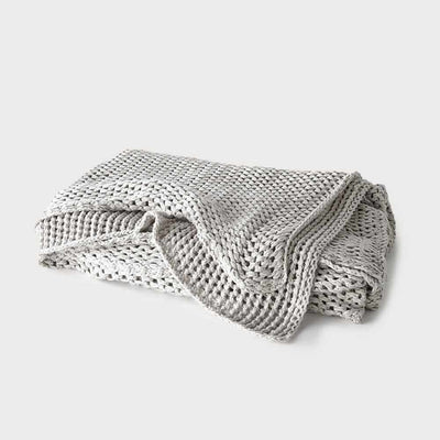 A neatly folded 100% cotton heavy knit Eadie Lifestyle Abrazo Silver Grey Throw on a white background.